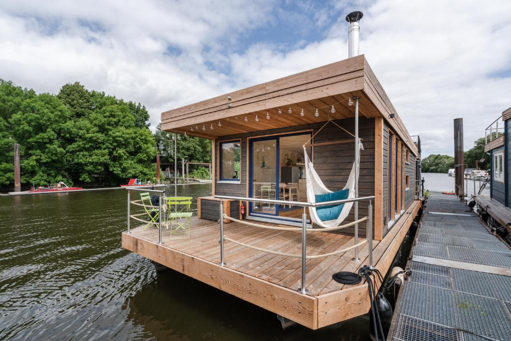 a small boat tied to a dock on the water at Hausboot AHOI hochwertiges Hausboote mit großer Terrasse und Kamin in Hamburg