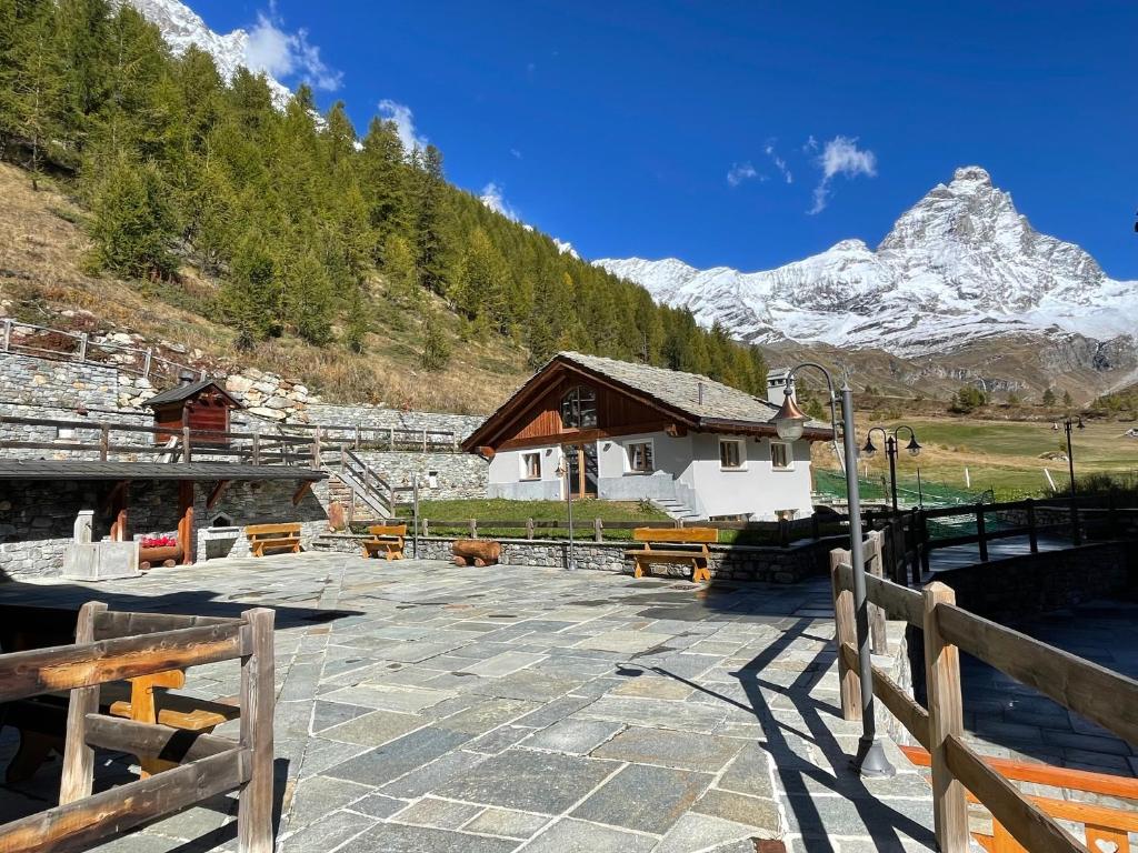 a large stone patio with a building in the mountains at Maison Carrel Elegant 7 in Breuil-Cervinia