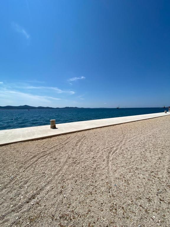a sidewalk next to the ocean on a beach at Ada in Zadar