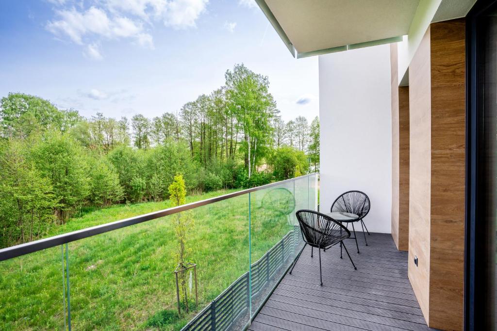 a balcony with two chairs and a view of a yard at Apartamenty Olimpijska z widokiem na jezioro in Olsztyn