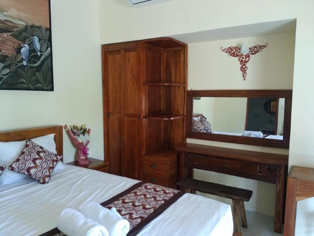 a bedroom with two beds and a dresser and a mirror at Pondok widji in Sukawati