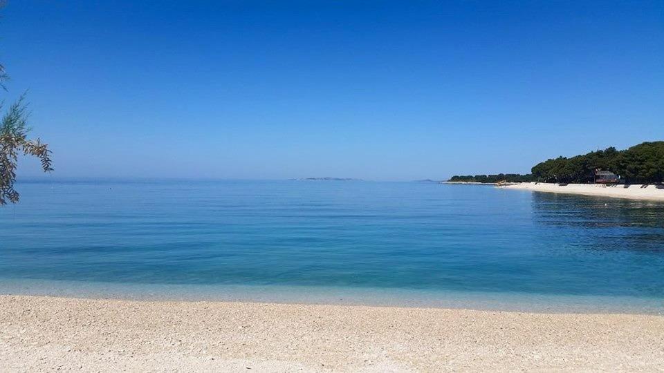 a beach with blue water and trees in the background at Studio Apartments Ivica in Primošten