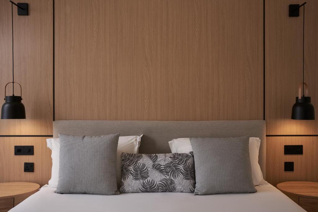 a bedroom with a bed with two pillows and two lights at Atlantica Bay - Adults Only in Limassol