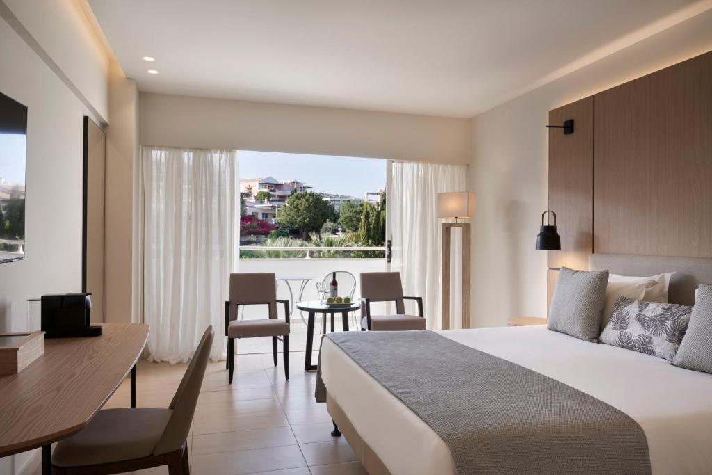a hotel room with a bed and a table and chairs at Atlantica Bay - Adults Only in Limassol