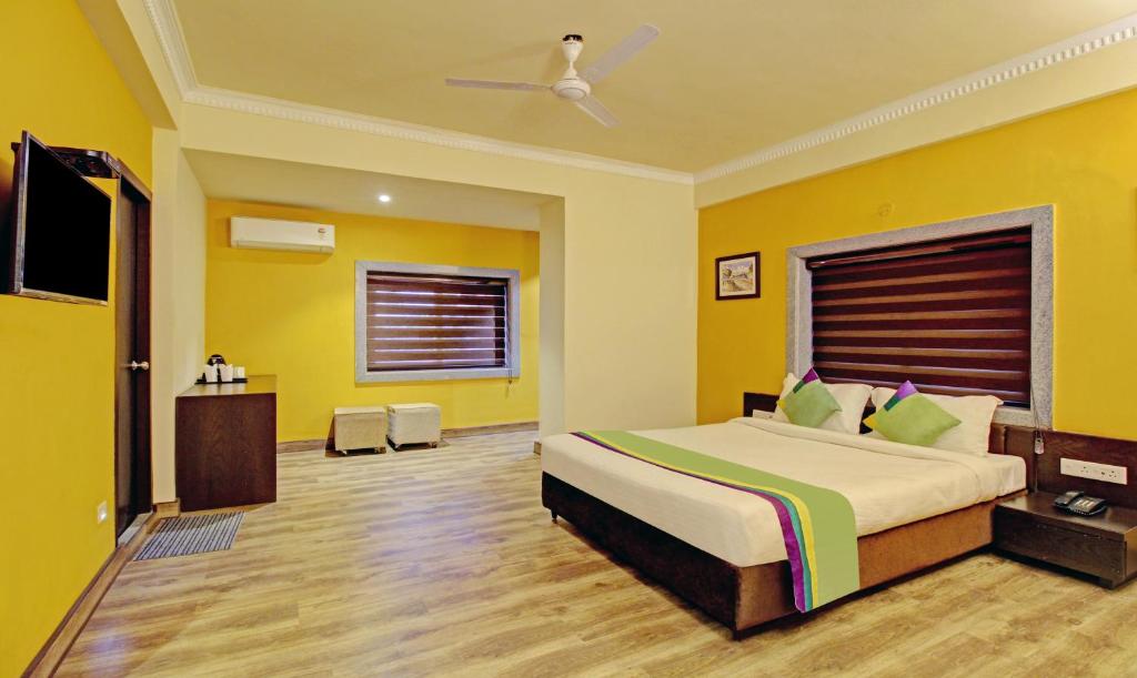 um quarto com uma cama grande e paredes amarelas em Treebo Trend ASL Prime em Calcutá