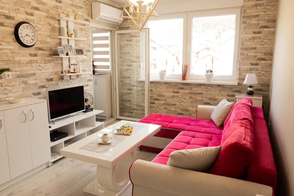 - un salon avec un canapé rouge et une télévision dans l'établissement Apartman Hedonia, à Višegrad