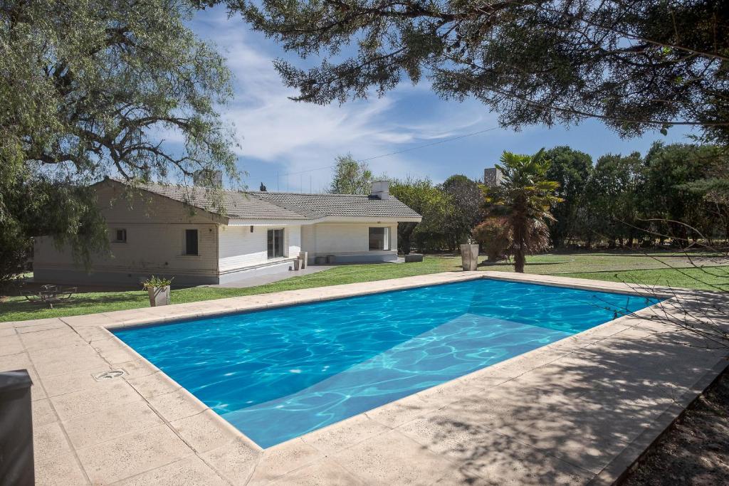 uma piscina azul em frente a uma casa em Paz y Confort em La Falda