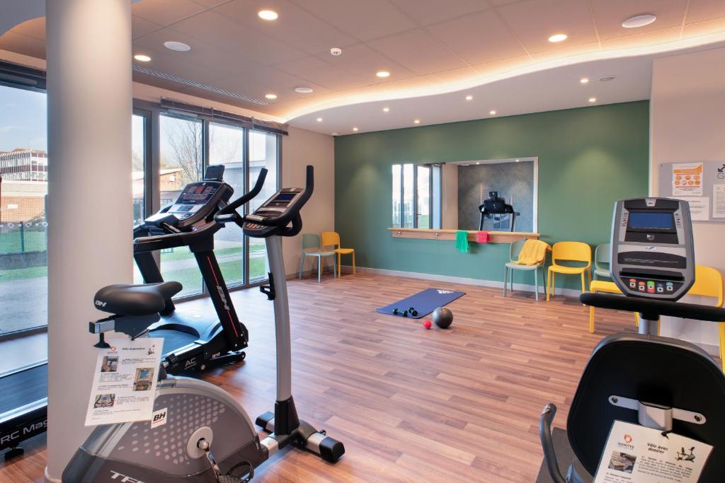 a gym with treadmills and exercise equipment in a building at DOMITYS LES CERNEAUX in Hazebrouck