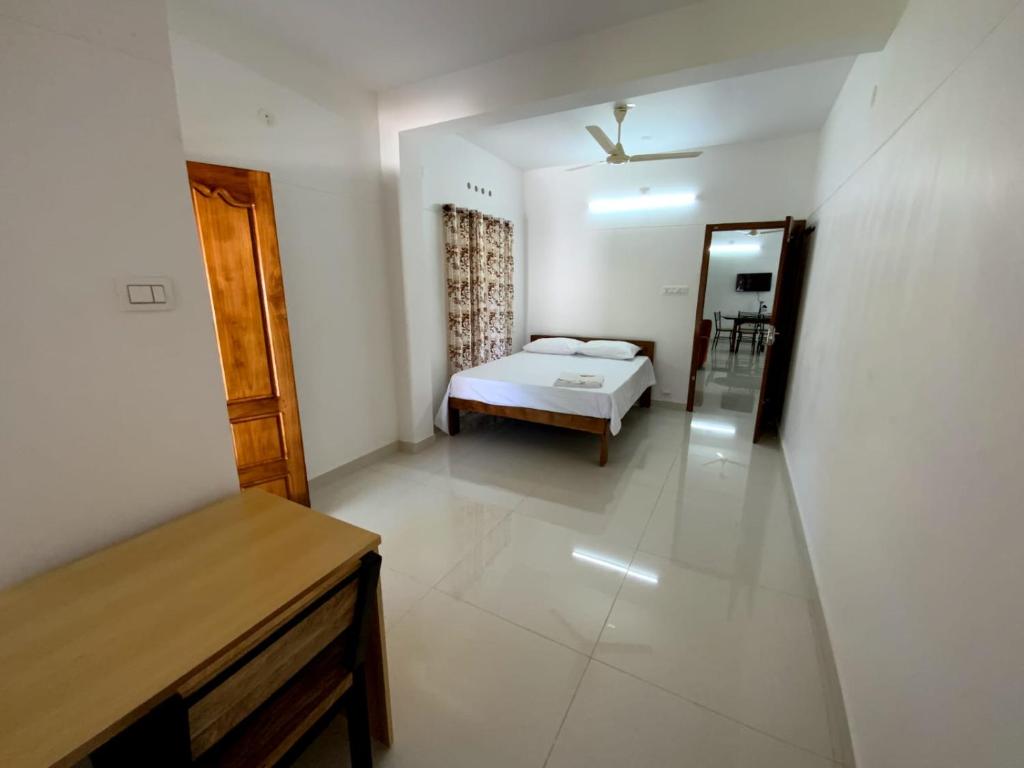 Un dormitorio con una cama y una mesa en una habitación. en PAZHOOR RESIDENCY HOME STAY 4BHK Deluxe, en Trivandrum