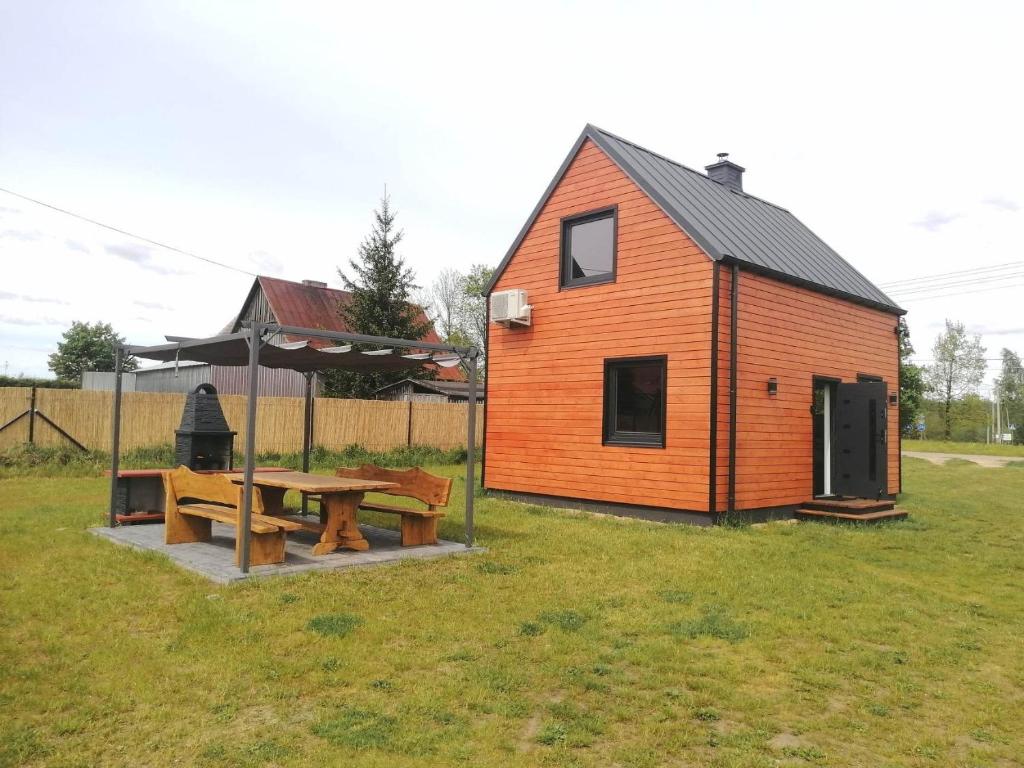 ein kleines Haus mit einem Picknicktisch und einer Picknickbank in der Unterkunft Domek całoroczny na mazurach in Orzysz