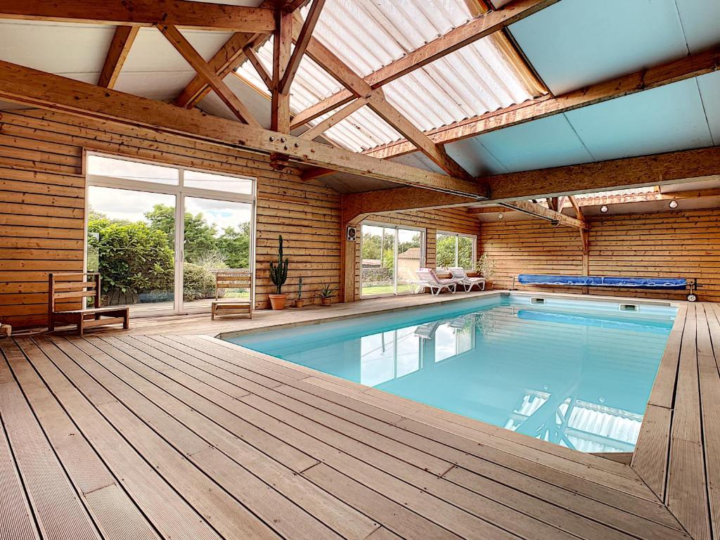 an indoor swimming pool with a wooden deck and a large window at Gite Chamarel in Les Aubiers