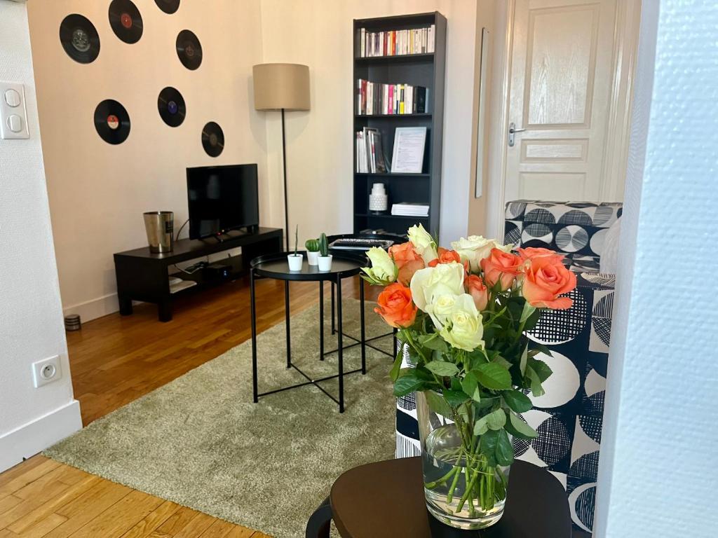 een woonkamer met een vaas met bloemen op een tafel bij Joli appartement au cœur de Lisieux avec vue sur la Cathédrale in Lisieux