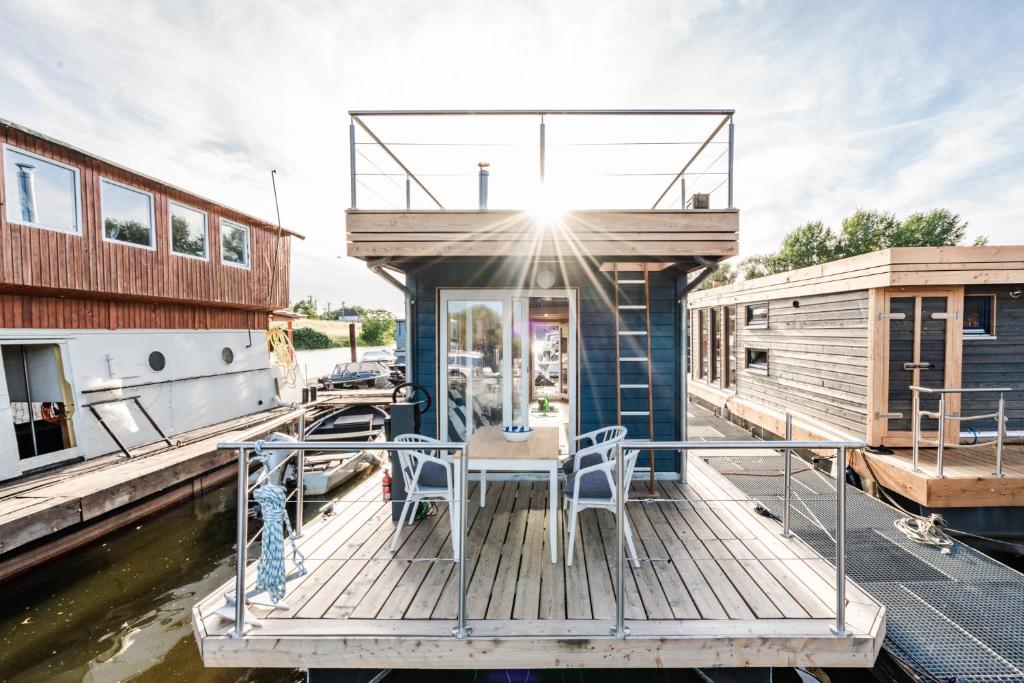 a dock with a table and chairs on a boat at Tolles Tiny-Hausboot GÜNTER mit Dachterrasse in Hamburg