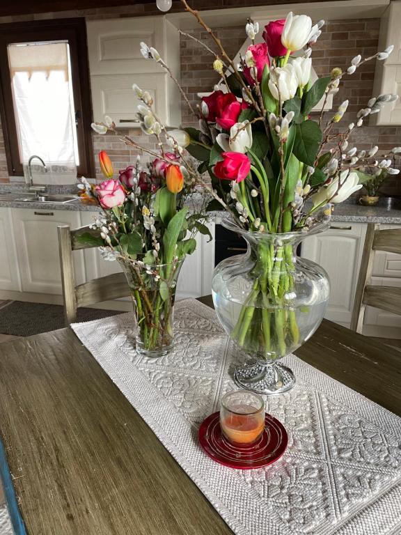 two vases of flowers on a table with a candle at La Casetta in San Nicolò dʼArcidano