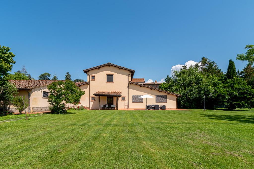 a large house with a large grass yard at Appartamento Falegnameria in Laterina