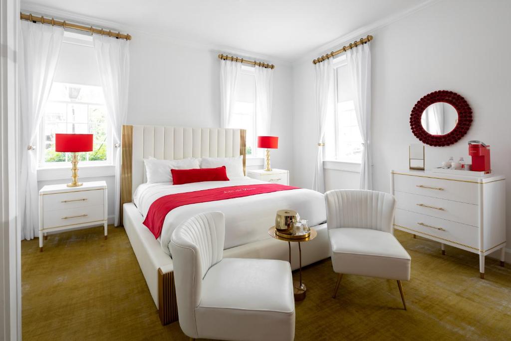 a white bedroom with a bed and a chair at The Vendue, Downtown Art Hotel in Charleston