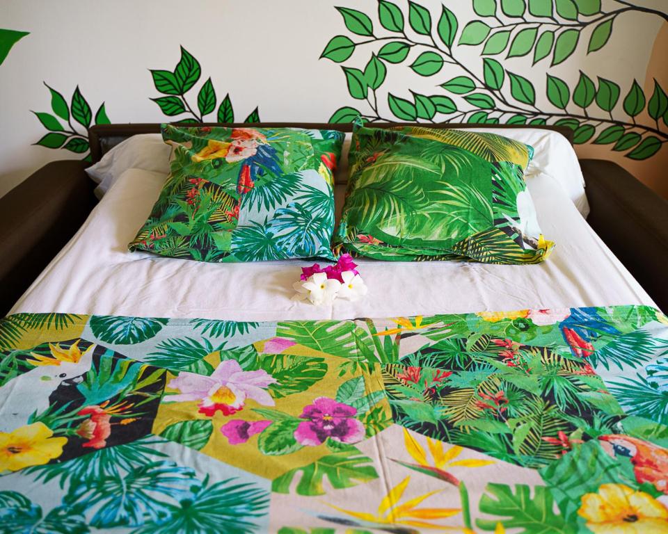 uma cama com lençóis coloridos e almofadas em Studio Carambole by Sweety Stay em Schœlcher