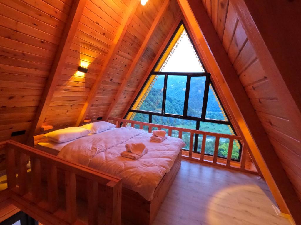 a bedroom in a log cabin with a large window at Necran Bungalow اكواخ ايدر in Rize