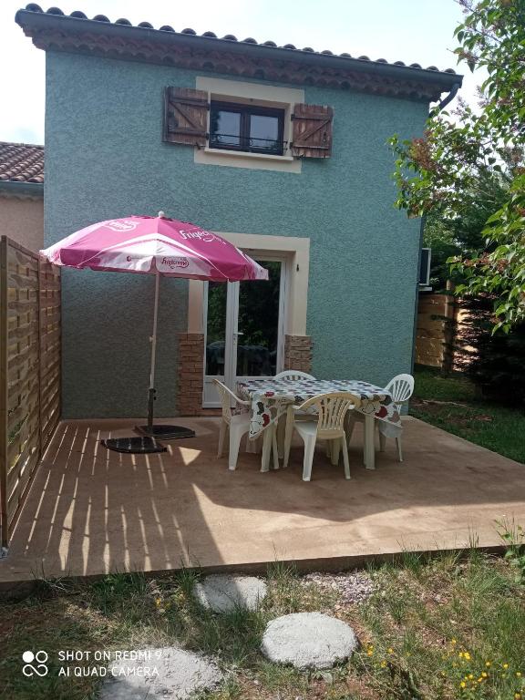 un patio avec une table, des chaises et un parasol dans l'établissement Les cyprès, à Lagorce