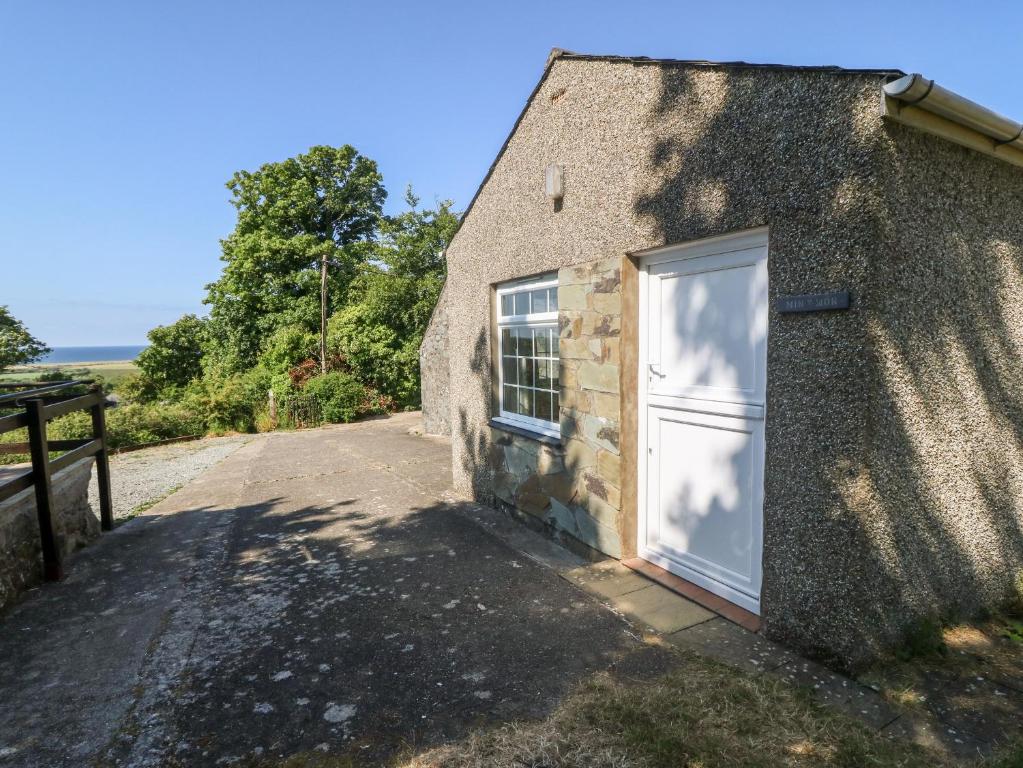 een stenen cottage met een witte deur aan de zijkant bij Min Y Mor in Criccieth