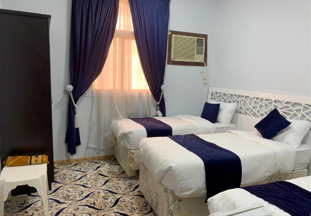 a hotel room with three beds and a window at Najmat Alnoor Almaabdah Hotel in Makkah