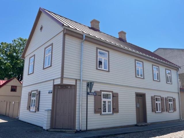 a large white house with a garage on a street at Ostsee Apartments in Ventspils