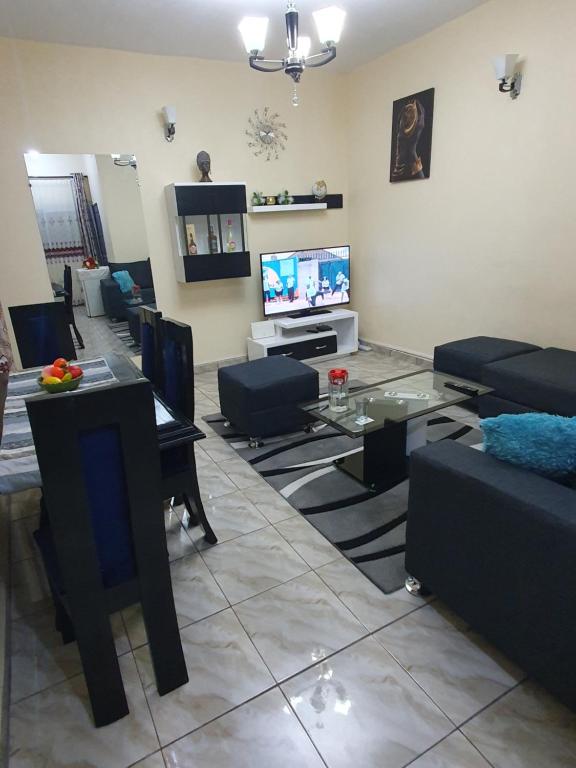 Appartement Cosy & Chill في دوالا: غرفة معيشة مع أريكة وطاولة وتلفزيون