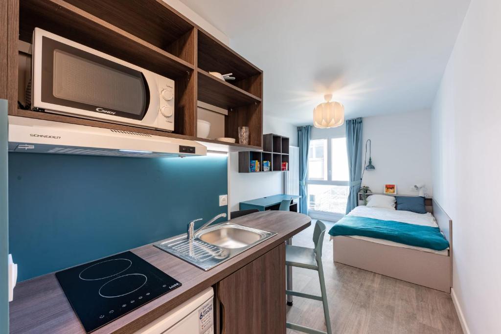 a kitchen with a sink and a microwave and a bedroom at Cute Studio close to Paris - 1P - 422 in Ivry-sur-Seine