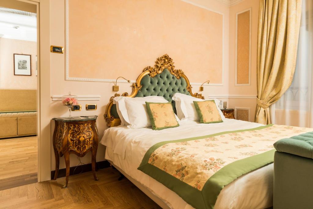 a bedroom with a bed with a green headboard at Hotel Bernini Palace in Florence