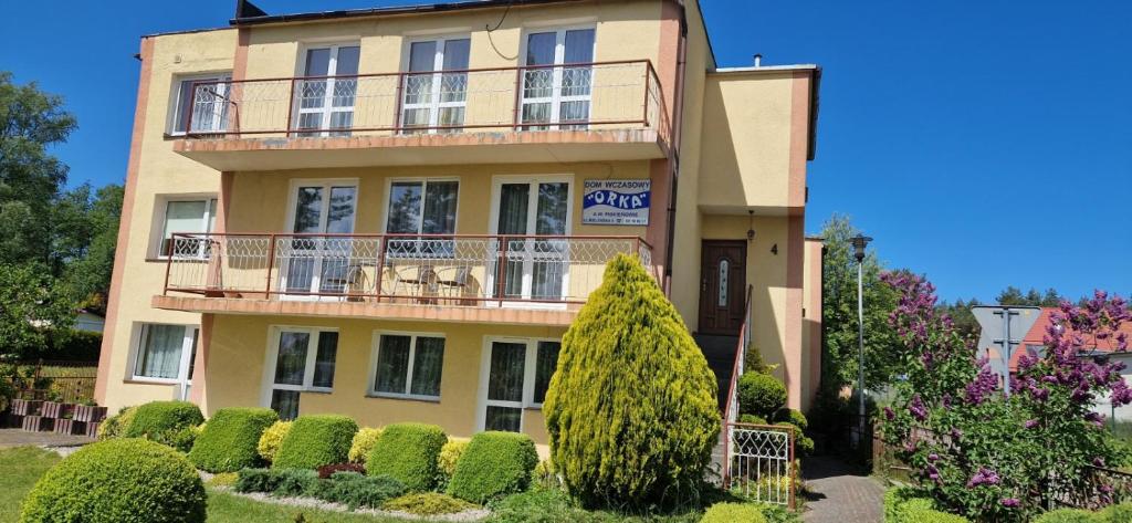 a large building with a balcony and some bushes at Dom Wczasowy Orka in Łazy