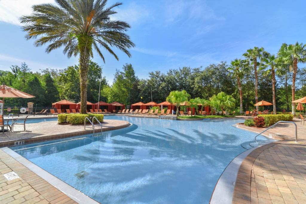 einen Pool in einem Resort mit Palmen und Sonnenschirmen in der Unterkunft Near Disney w/ pool-3BR/2BA-Spacious & Cozy Condo in Davenport