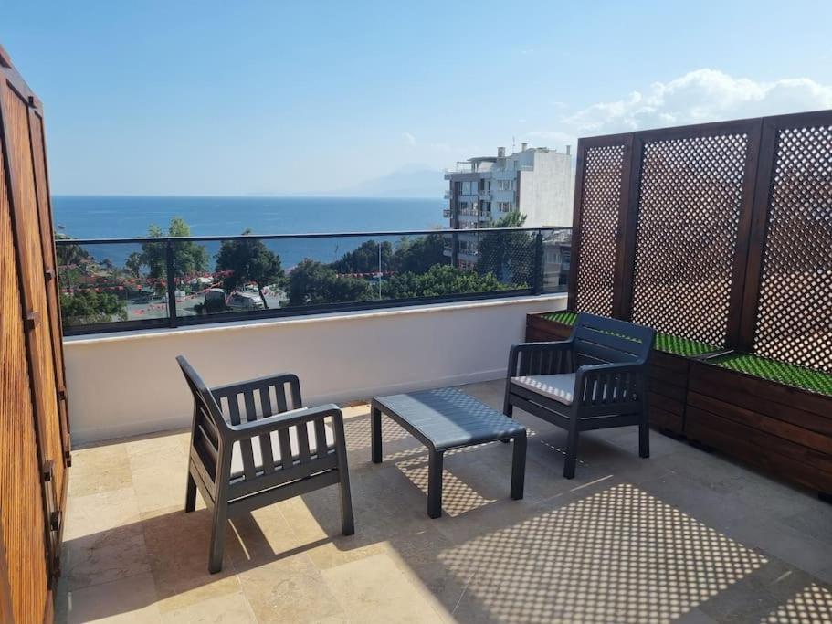 duas cadeiras e um banco numa varanda com vista para o oceano em Royal Homes 502 em Antália