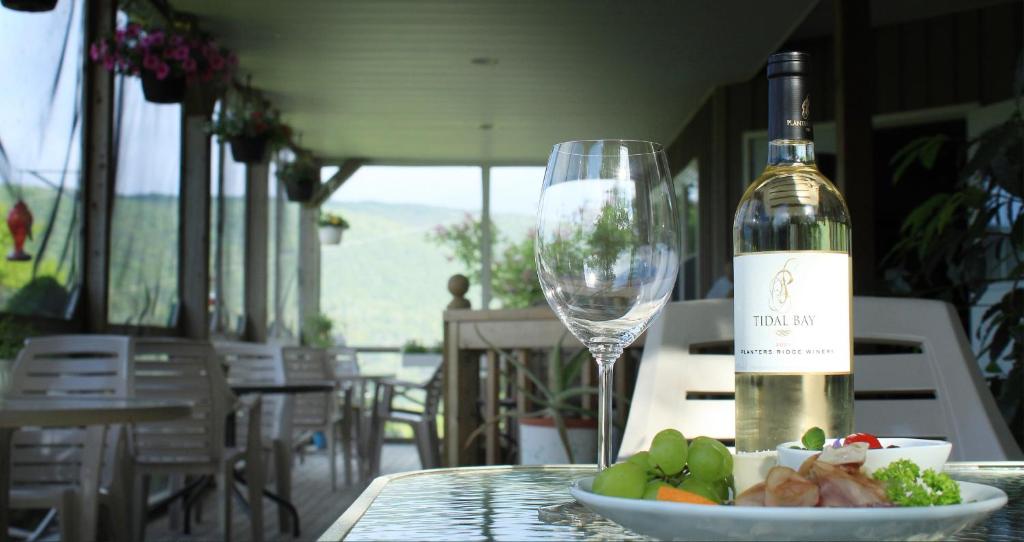 a bottle of wine and a plate of food and a wine glass at Chanterelle Inn & cottages in Baddeck