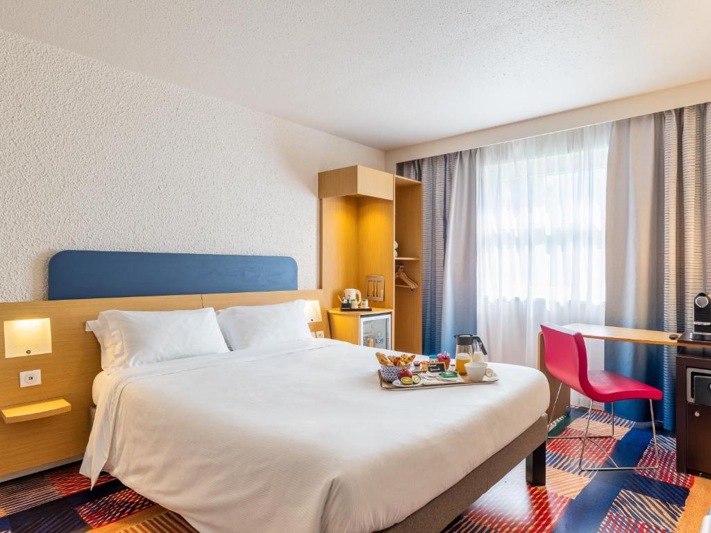 a hotel room with a bed with a tray of food on it at B&B HOTEL Lyon Nord 4 étoiles in Dardilly