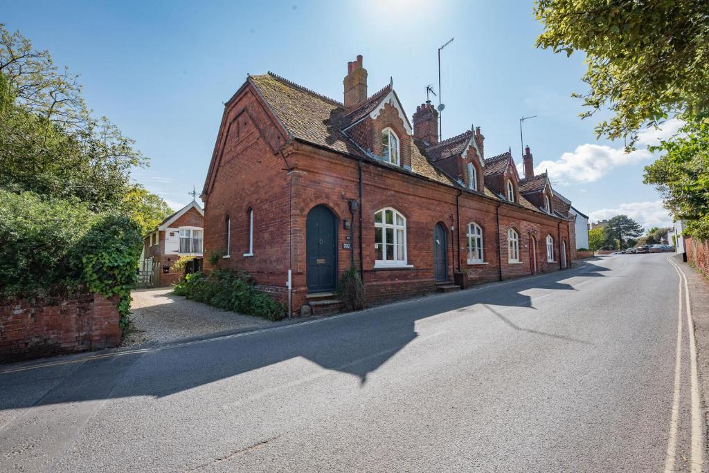 an old red brick building on the side of a street at Margo's Cottage in Orford