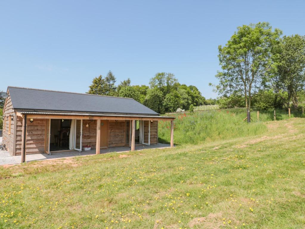 una cabaña de madera con un campo delante en Watermead Lodge en Taunton