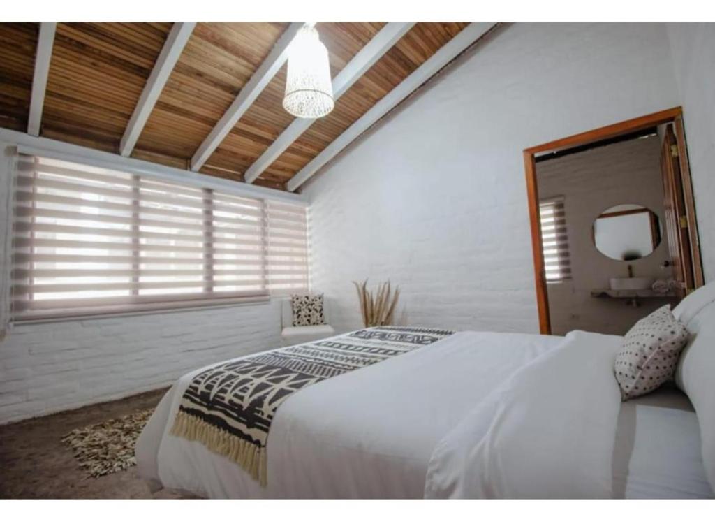 a bedroom with a large white bed and a window at Rústic Quinta La Aurora in Baños