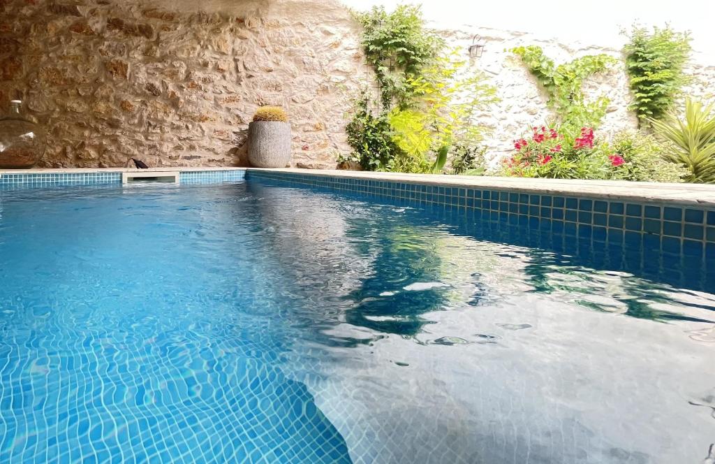 a blue swimming pool with a stone wall at L&#39;Oiseau Bleu ROLLIER in Roubia