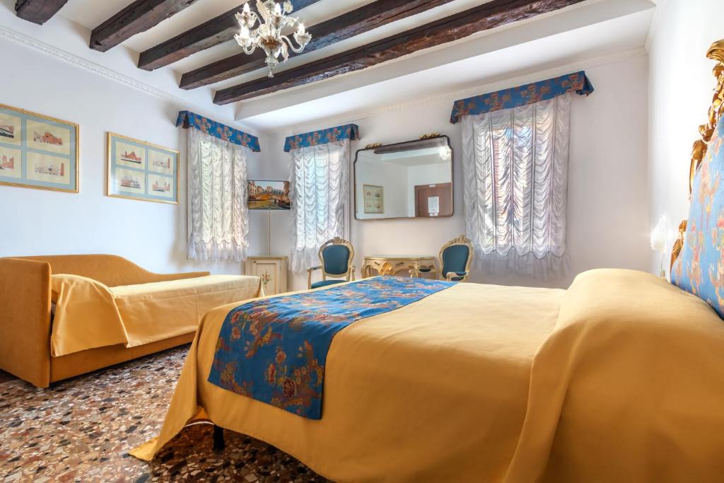 a bedroom with two beds and a couch and a mirror at Hotel Casa Boccassini in Venice