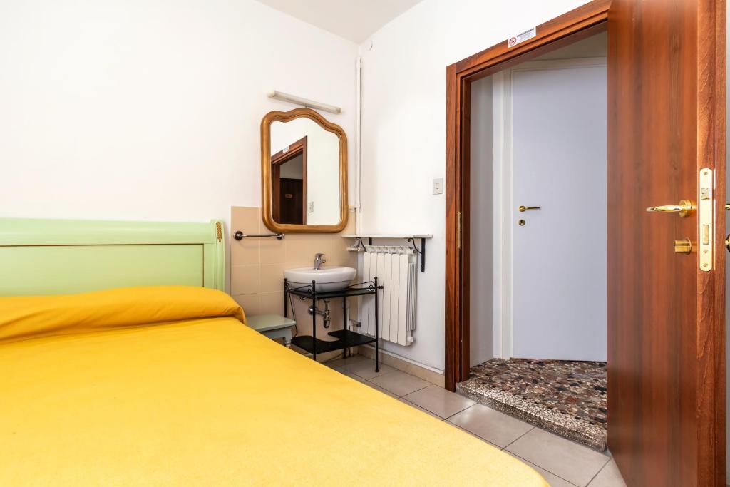 a bedroom with a bed and a sink and a mirror at Hotel Casa Boccassini in Venice