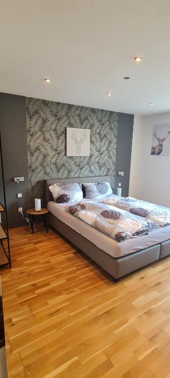 duże łóżko w pokoju z drewnianą podłogą w obiekcie Ferienhaus Romy w mieście Hohenfels-Essingen