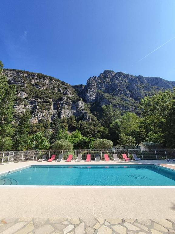 une piscine avec des chaises et une montagne en arrière-plan dans l'établissement Le Moulin du Pont D'Aliès, à Axat