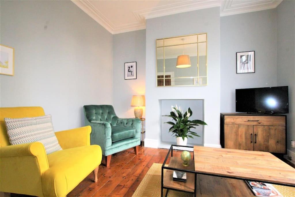 a living room with a green couch and a tv at Lovely 2BR home with sunny garden in Montpelier in Bristol