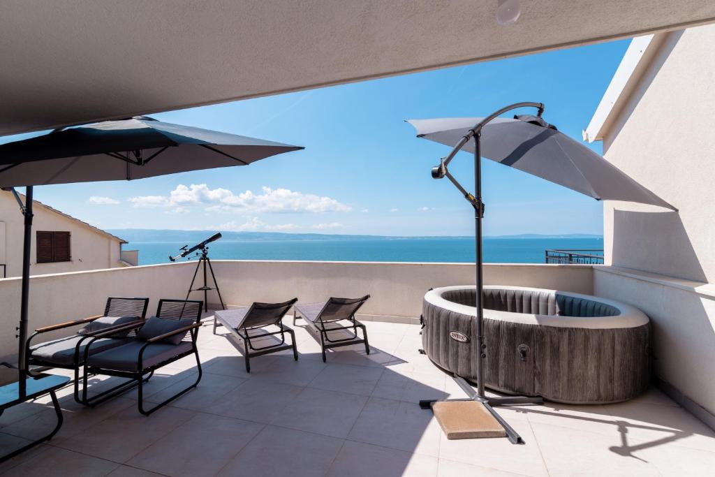 balcone con vasca idromassaggio, sedie e ombrellone di Sea View House & Free Parking a Podstrana