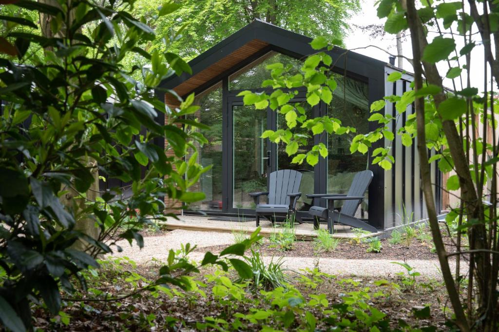 a glass house with two chairs in a garden at Boetiekpark 't Zwaantje in Mook
