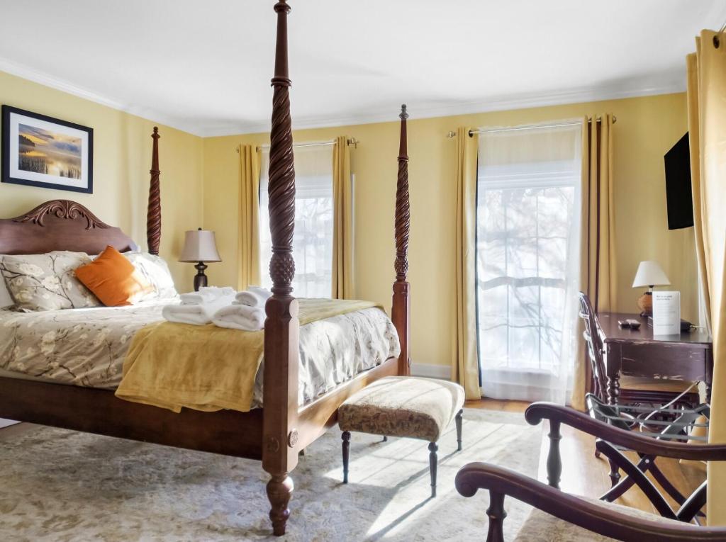 a bedroom with a four poster bed and a chair at The Thistle Inn in Boothbay Harbor