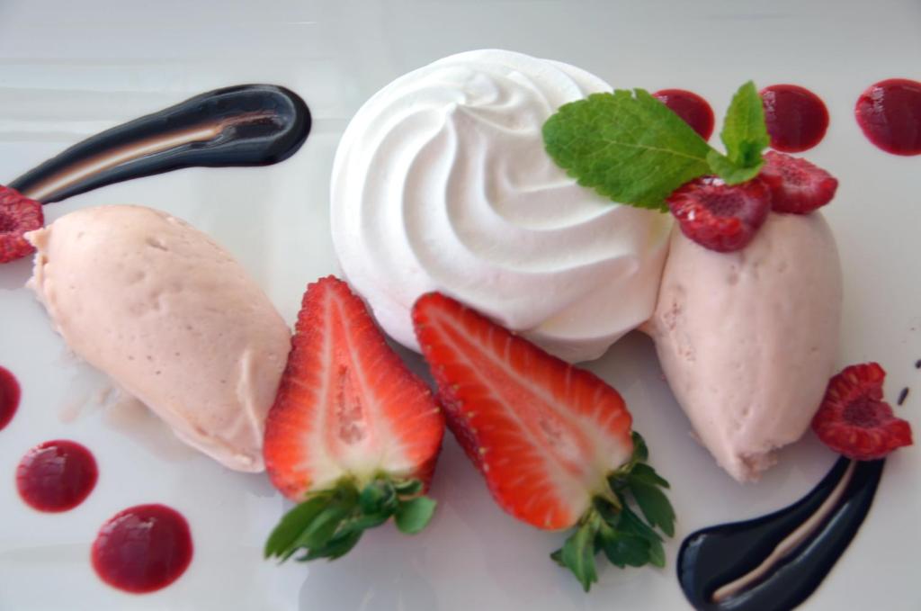 a white plate with strawberries and whipped cream at The Riviera Hotel & Apartments - Alum Chine in Bournemouth