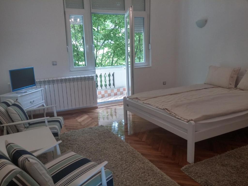 a living room with a bed and a tv and chairs at Cricket 2 Hostel in Belgrade
