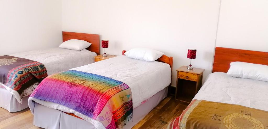 a room with two beds with a rainbow blanket at Nishihouse in Cusco