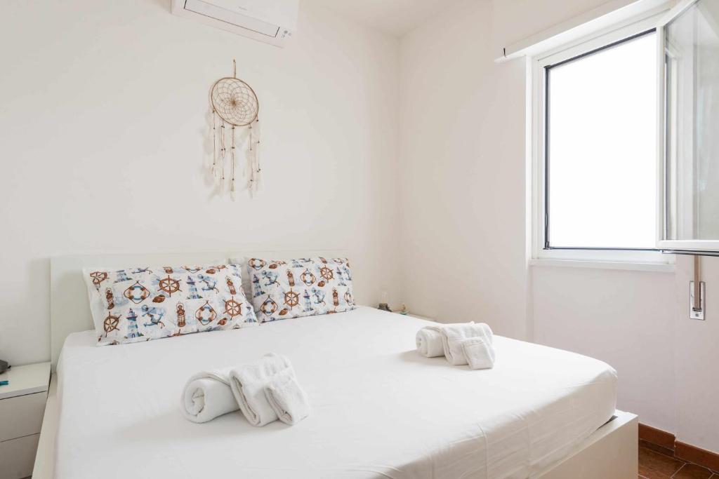 een witte slaapkamer met een bed met handdoeken erop bij Seamoon Home Nettuno in Nettuno